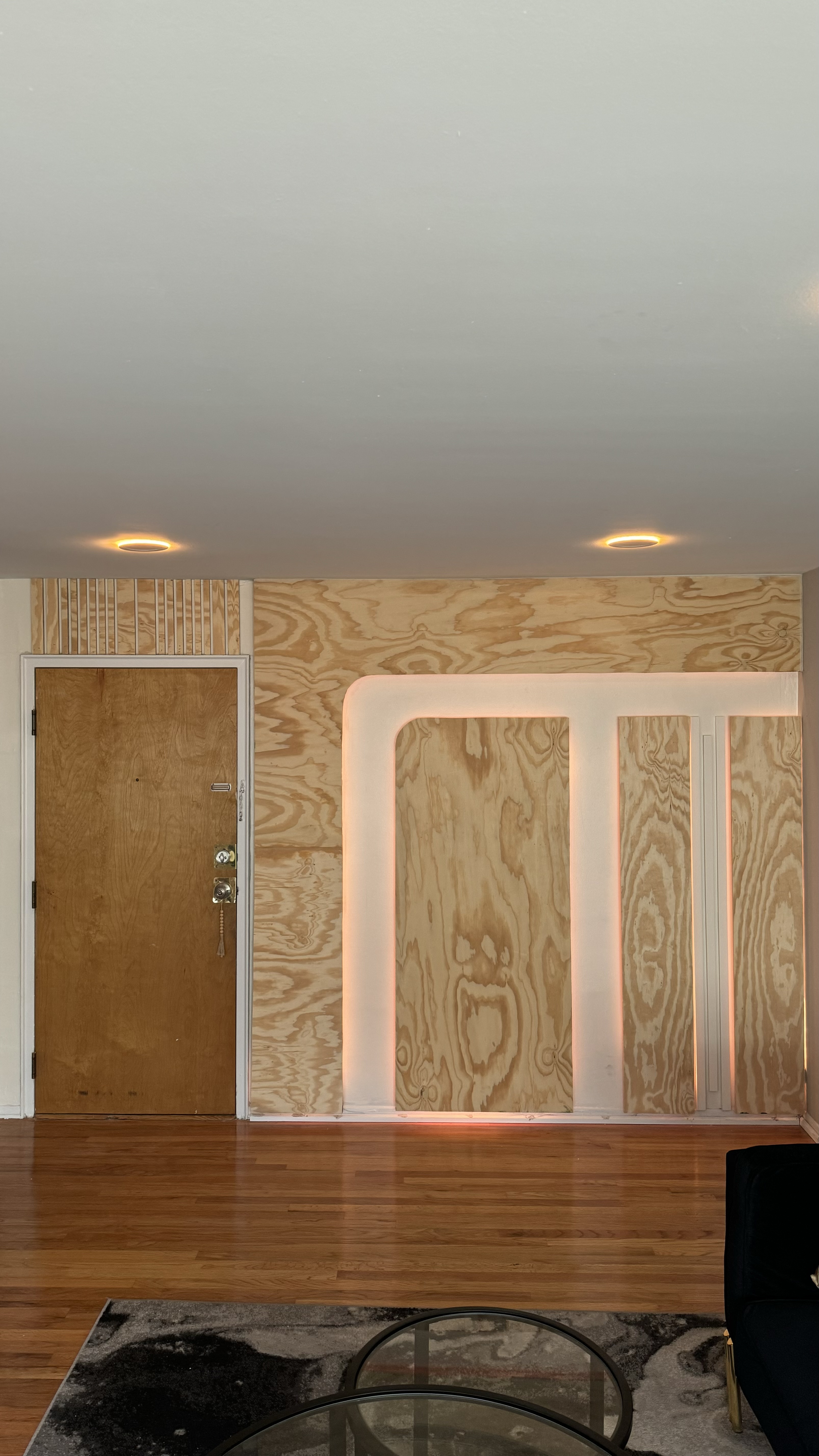 The Birch, a geometric accent wall built by SEIN ME in New Jersey. Custom wood slats and geometric trim with LED channel lighting on a dimmer, framed around the doorway.