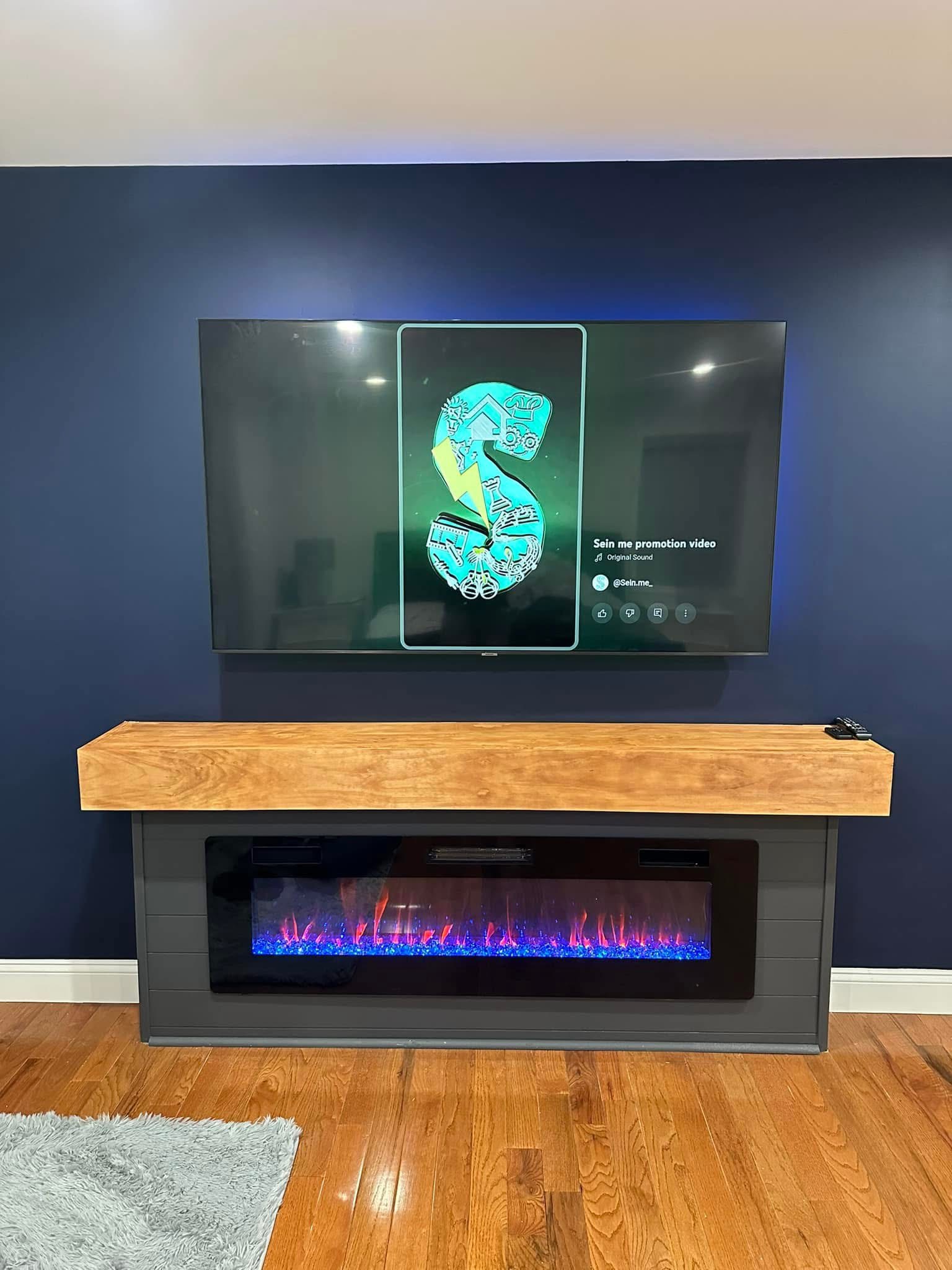 The Harbor, a custom media wall built by SEIN ME in New Jersey. Navy painted accent wall with a fireplace build out, a wood mantel and the TV mounted above with LED glow.