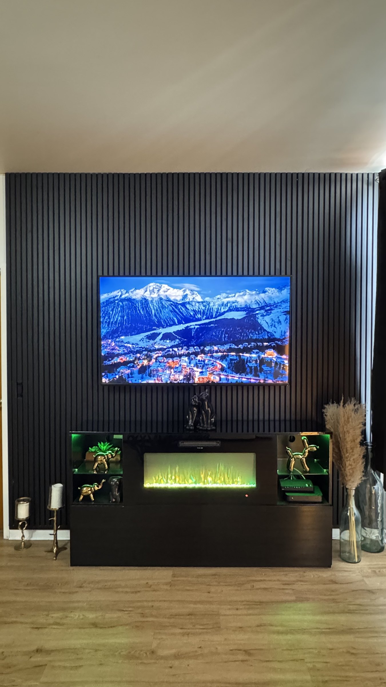 Full-height black slat accent wall with TV and lit display console by SEIN ME in Plainfield, New Jersey