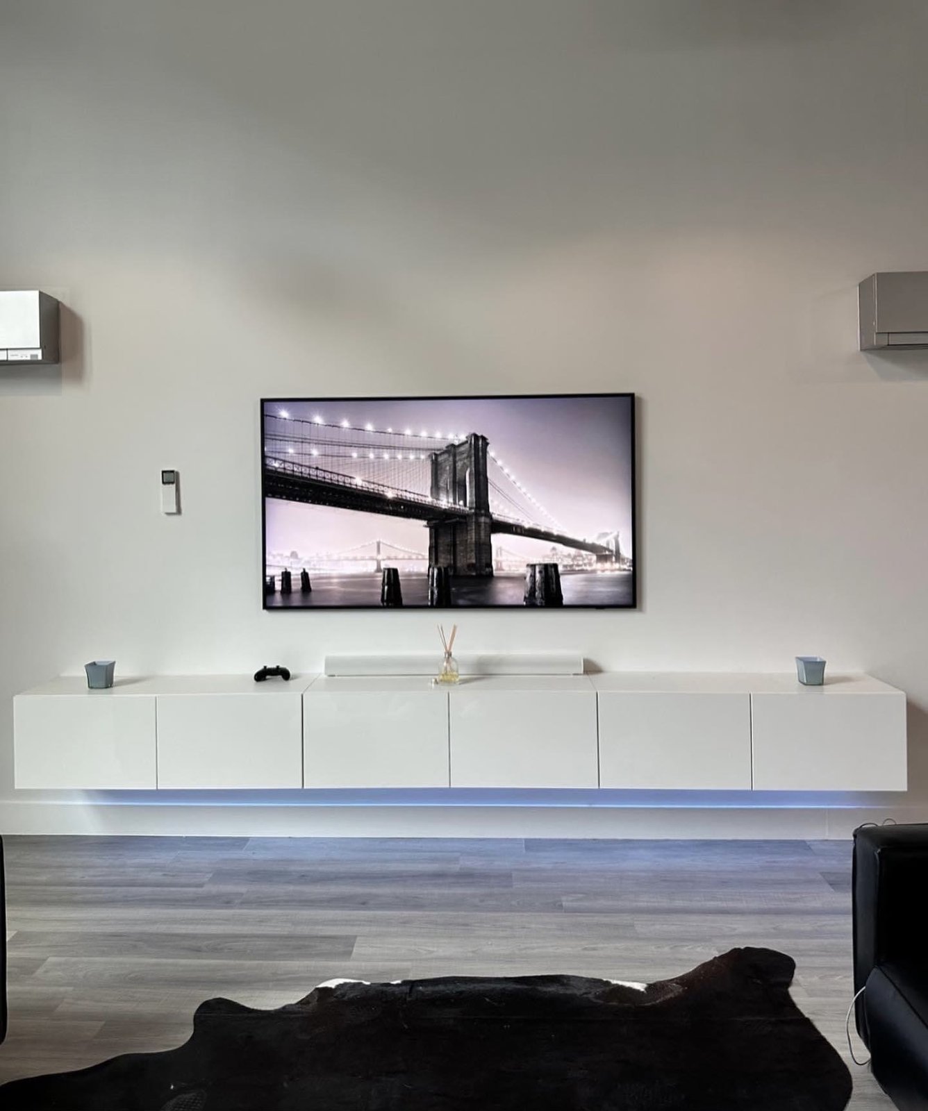 The Skyline, a TV wall built by SEIN ME in New Jersey. TV mounted over a white floating cabinet with LED glow underneath and no wires showing.