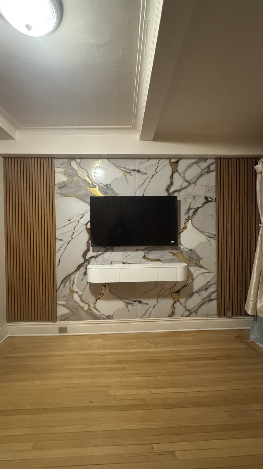 White-gold marble media wall with walnut slat columns and white console by SEIN ME in Passaic, New Jersey