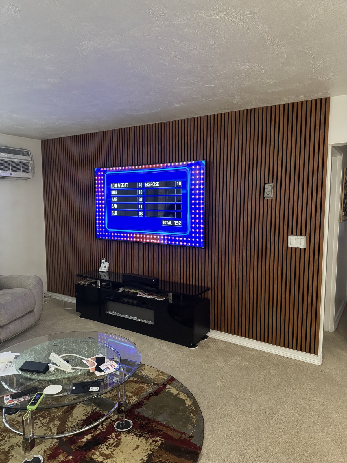 Floor-to-ceiling walnut slat wall with black console and crystal fire insert by SEIN ME in Plainfield, New Jersey