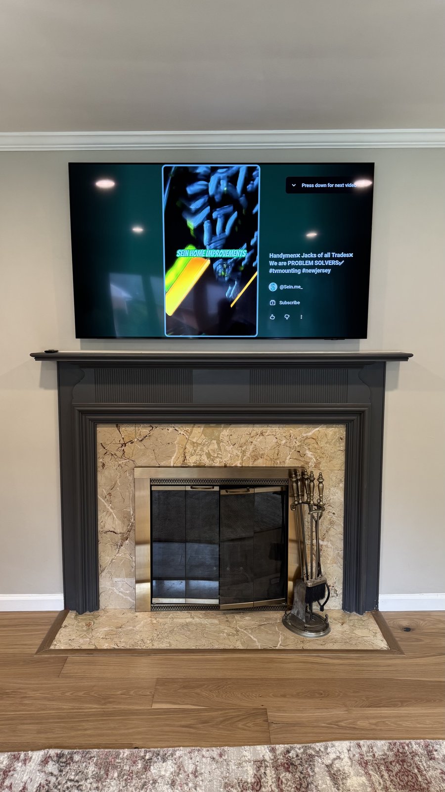TV mounted above a charcoal traditional mantel with tan marble surround by SEIN ME in Metuchen, New Jersey