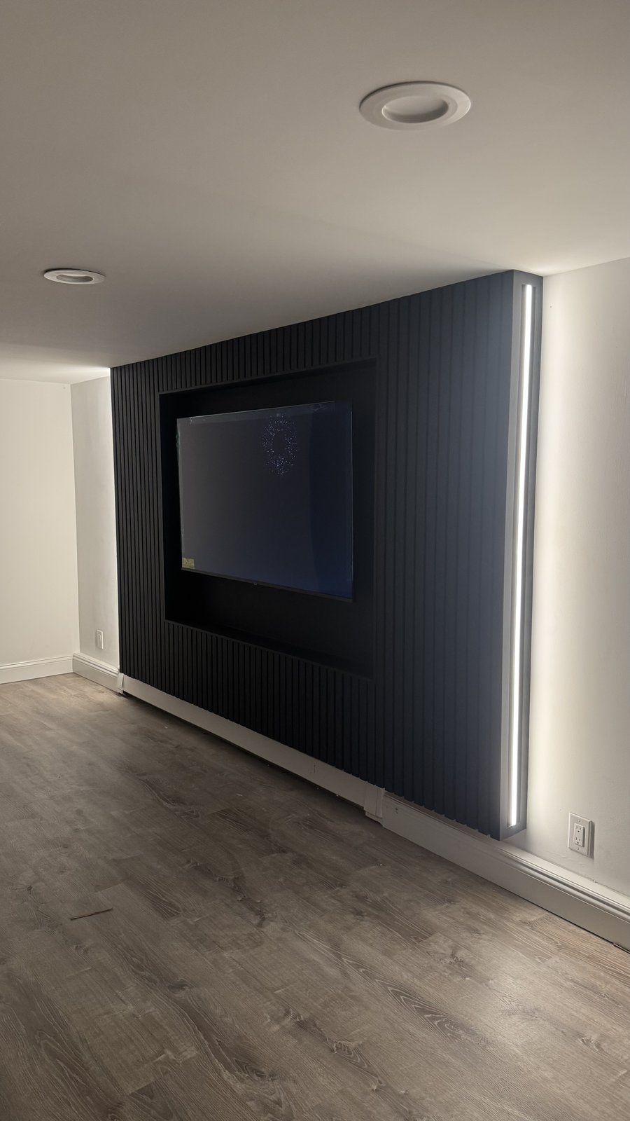 Black slat niche media wall with recessed TV washed in white LED edge glow by SEIN ME in Piscataway, New Jersey