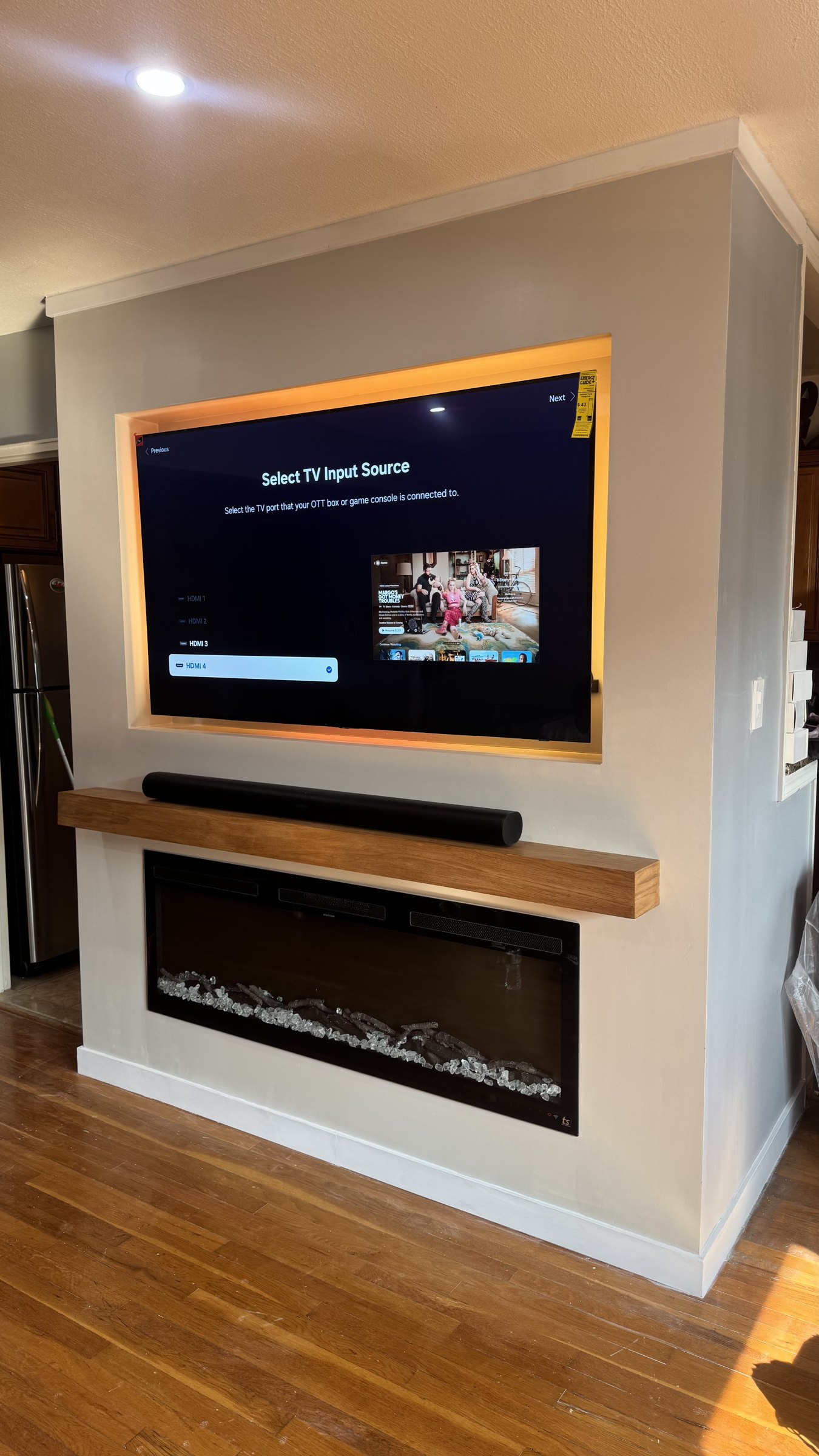 Recessed TV niche glowing amber over an oak mantel, soundbar and linear fireplace built by SEIN ME
