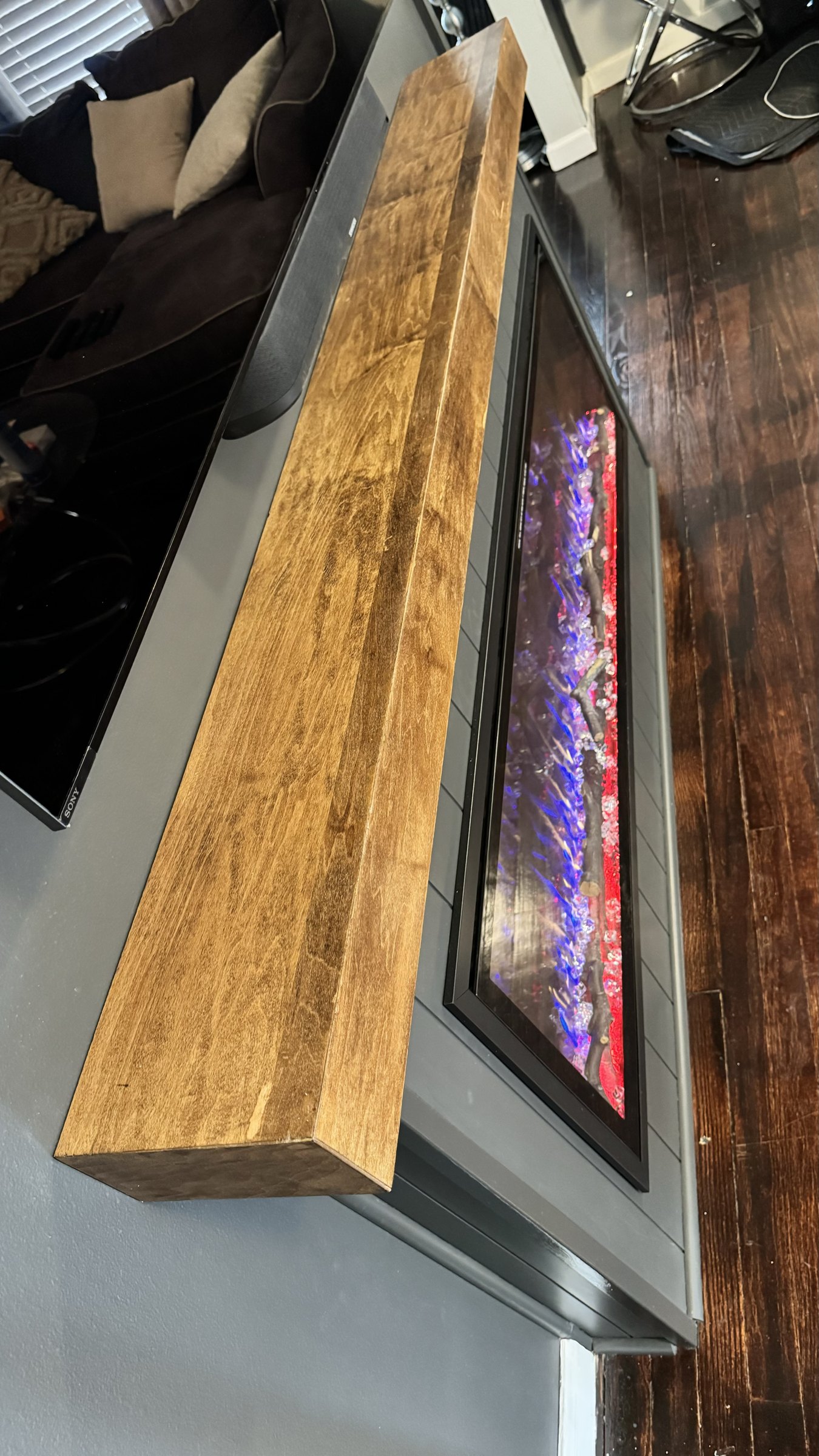 Dark walnut stained floating mantel built by SEIN ME, mounted over a shiplap wall with linear fireplace and TV