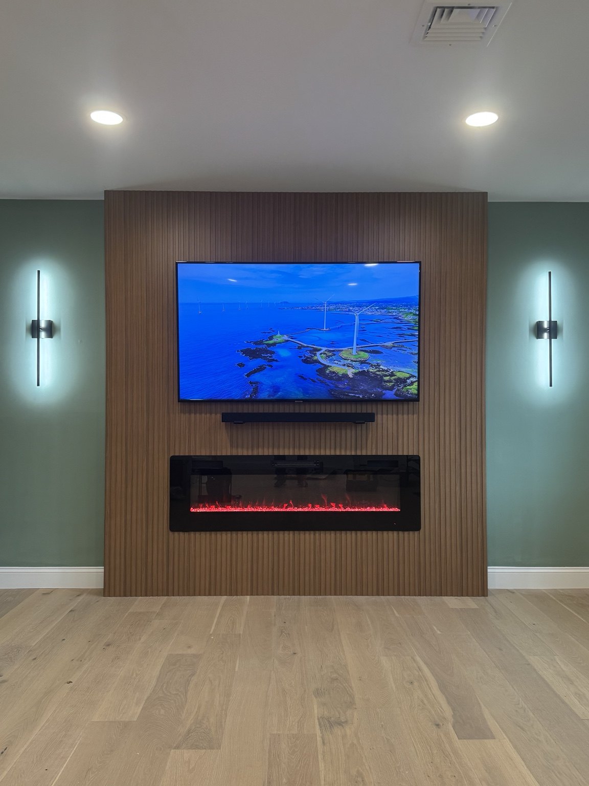 Walnut slat media wall with linear fireplace and sconces installed by SEIN ME in Piscataway, New Jersey