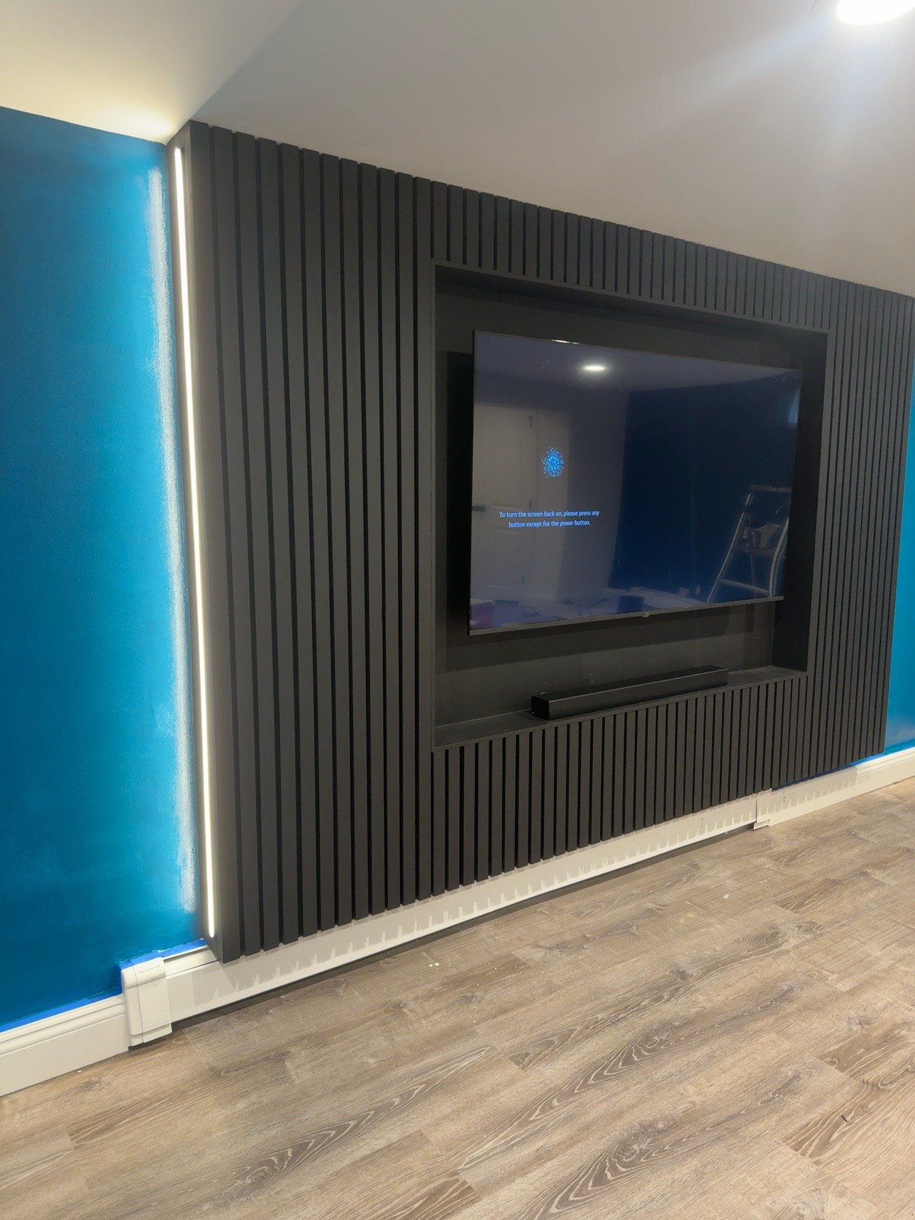 Black slat niche media wall with white LED edge in a blue room, built by SEIN ME in Piscataway, New Jersey