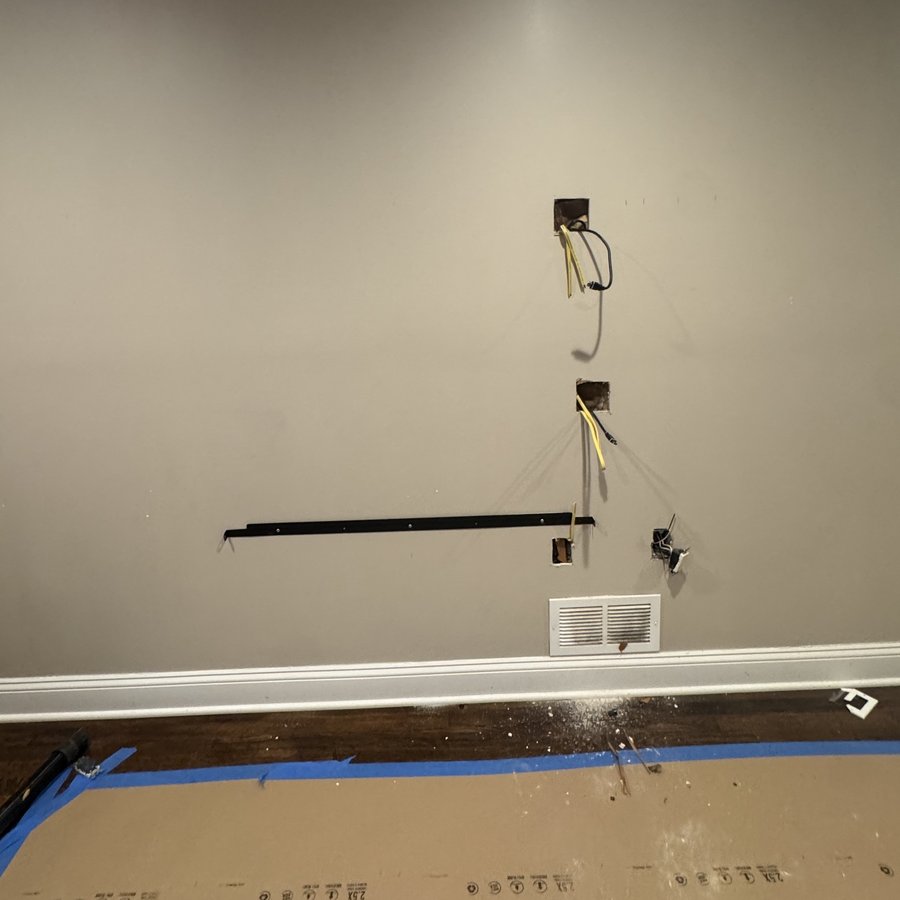 The same wall before the build, bare drywall with wiring cut in