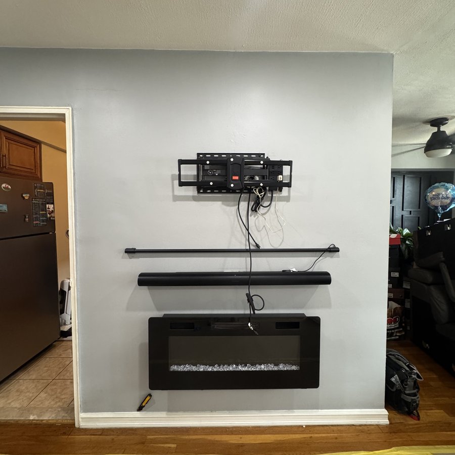 The same wall mid-install with the TV mount up and fireplace staged